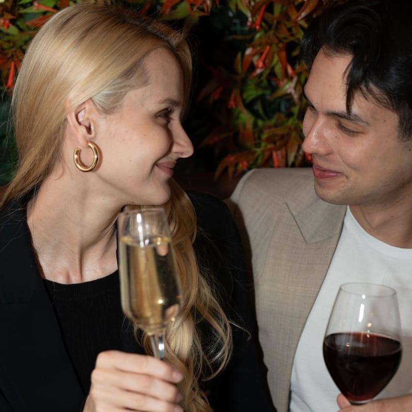 A couple at Khaosan Thai restaurant, smiling at each other while holding drinks.